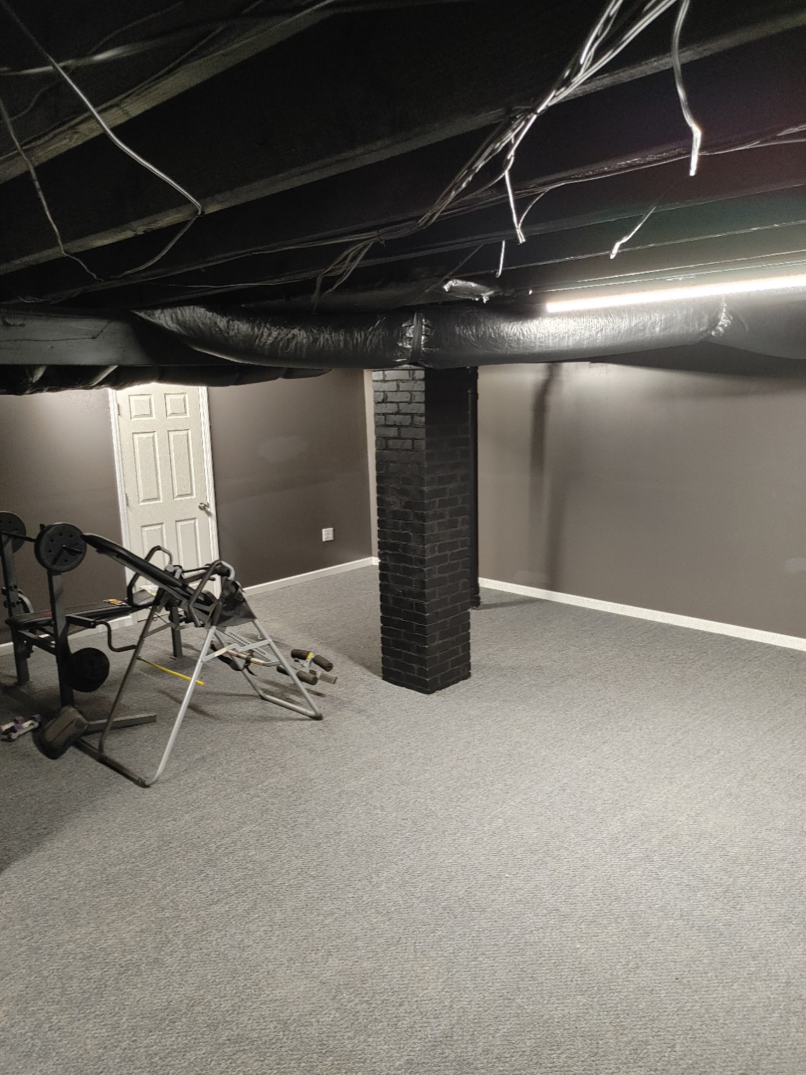 Finished carpeted basement with painted brick column