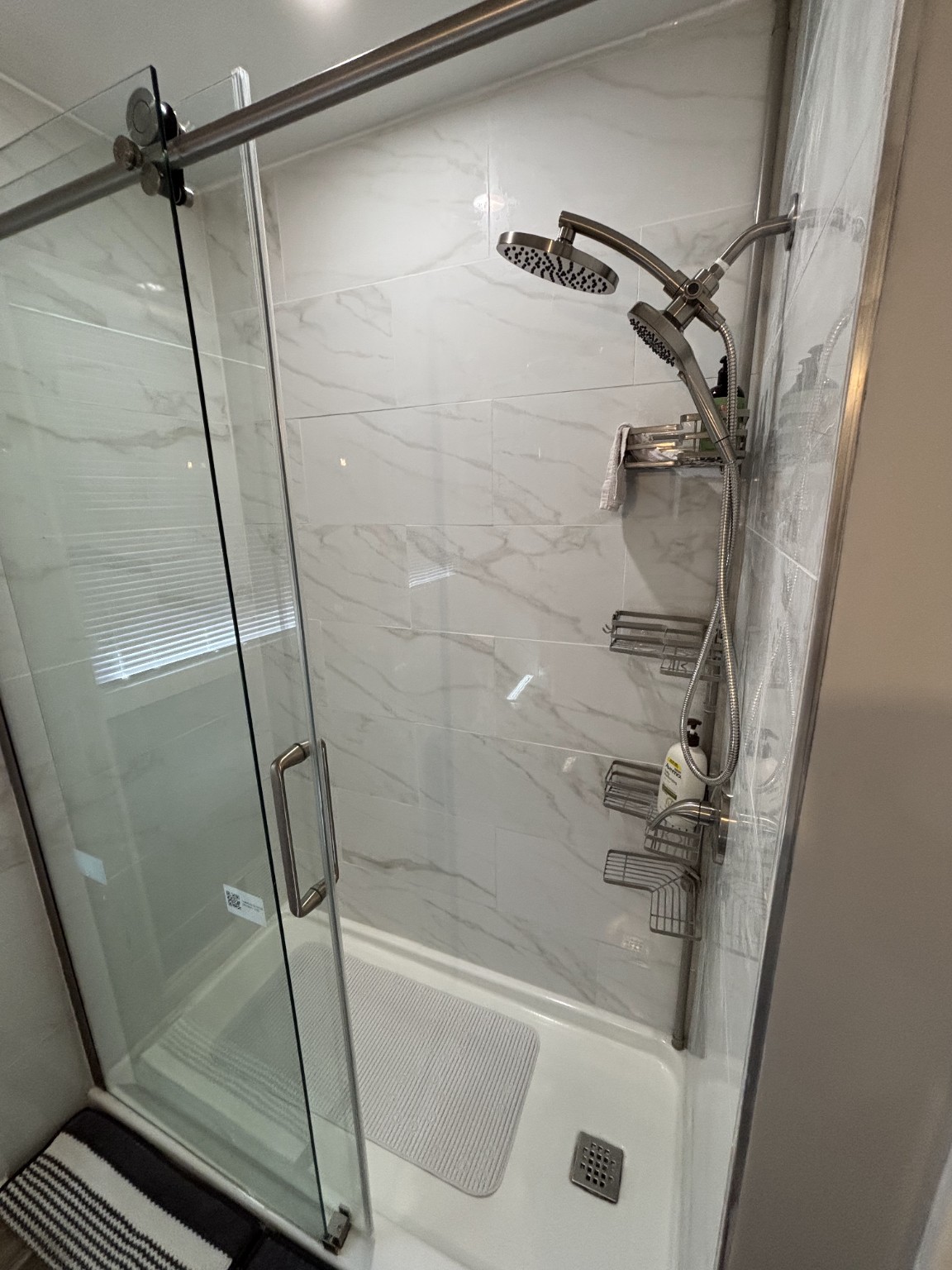 Finished marble-look shower tile and glass enclosure