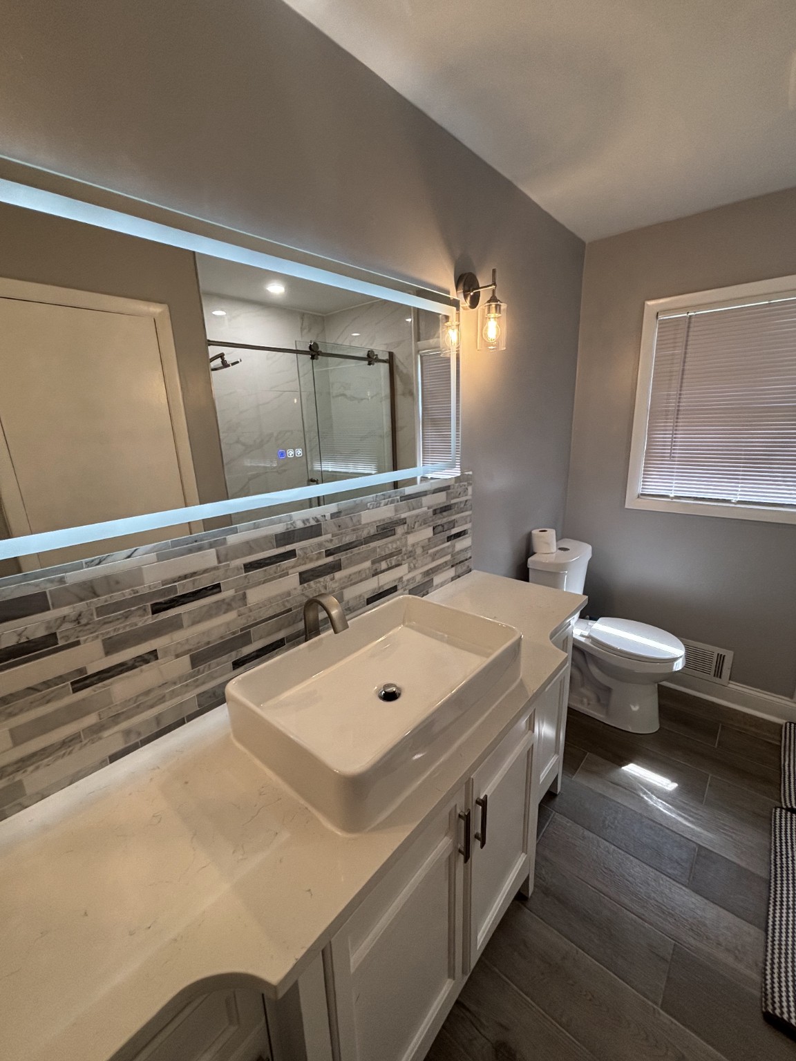 Finished bathroom vanity, wide mirror, and tile accent wall