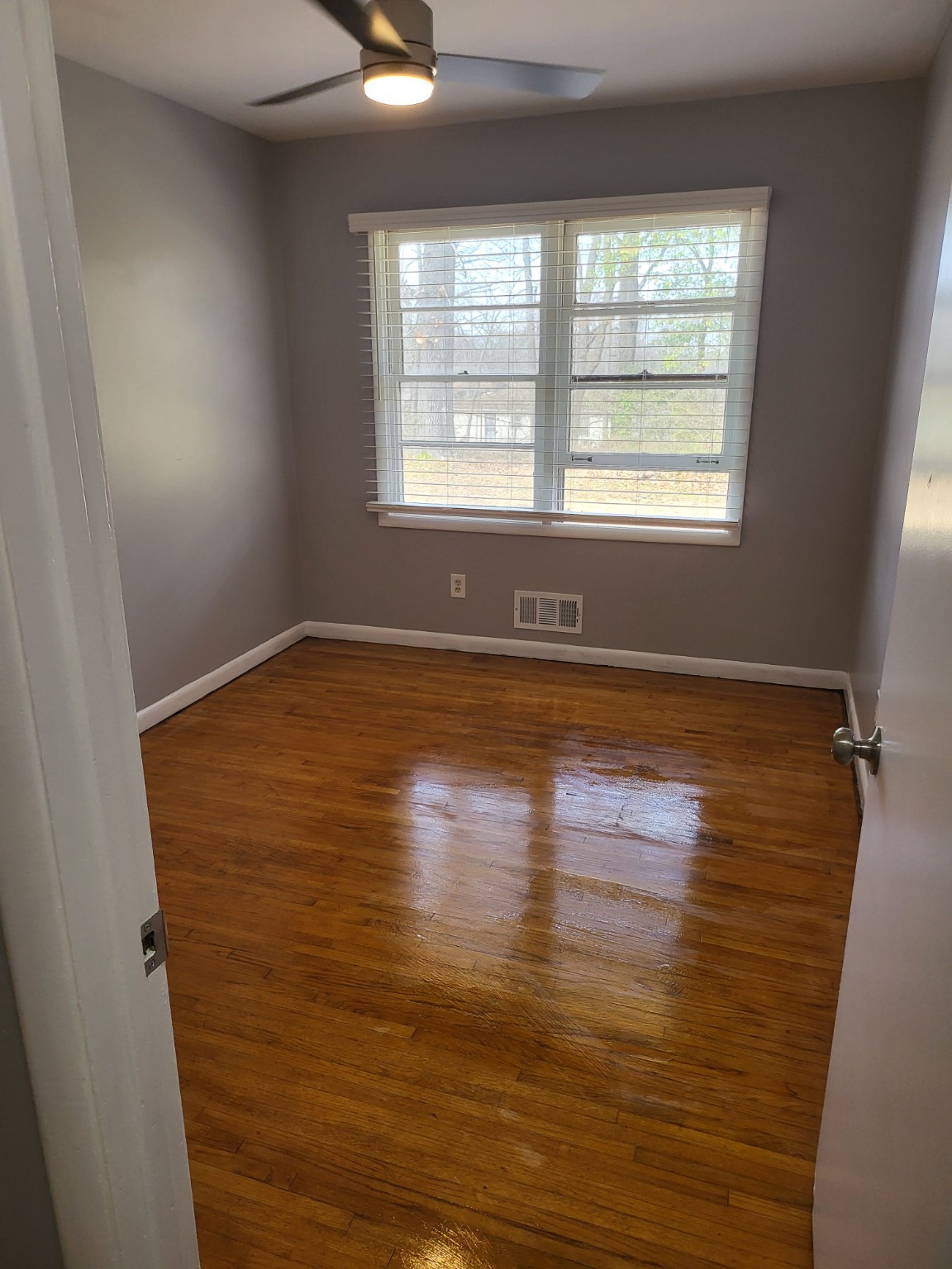 Polished hardwood flooring in a finished room with gray walls