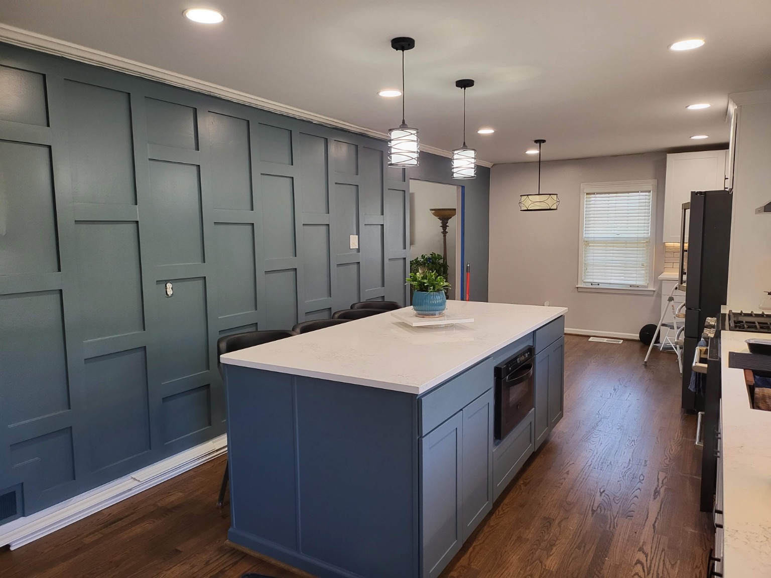 Finished kitchen with blue island, white counter, and blue paneled accent wall