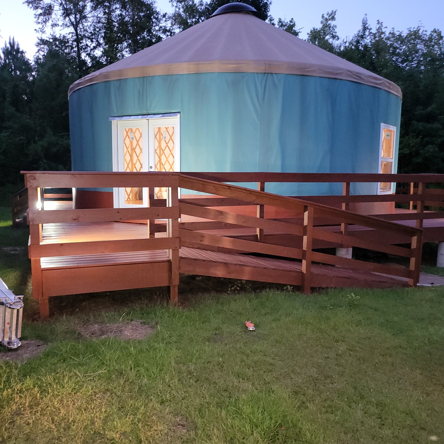 Raised yurt and deck with access ramp viewed from the yard